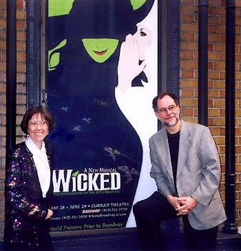 Carol and Gregory standing in front of the Curran Theatre with the Wicked poster